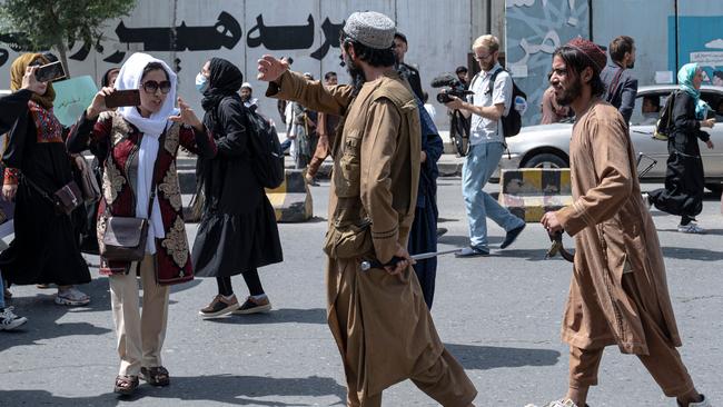 Taliban fighters walk as they fire in air to disperse Afghan women protesters in Kabul on August 13.