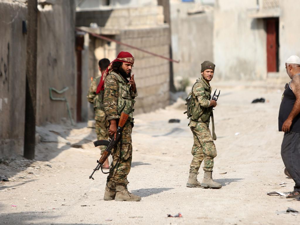 Turkey-backed Syrian fighters walk in a street near a position that they are holding in the Syrian border town of Ras al-Ain. Picture: Nazeer Al-khatib/AFP