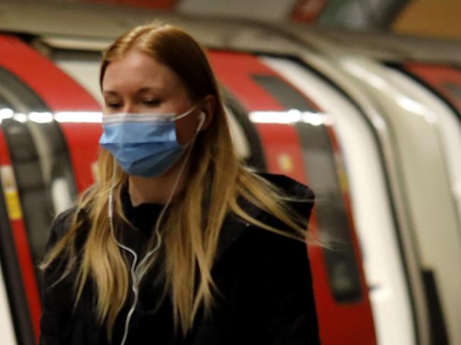 Commuters, wearing PPE (personal protective equipment) as a precautionary measure against COVID-19, walks along the platform at a tube station London on April 22, 2020, as Britain remains under lockdown during the novel coronavirus COVID-19 pandemic. - British Prime Minister Boris Johnson tentatively began his return to work on Tuesday after being hospitalised for coronavirus, as parliament returned and criticism grew over the government's response to the outbreak. (Photo by Tolga Akmen / AFP)