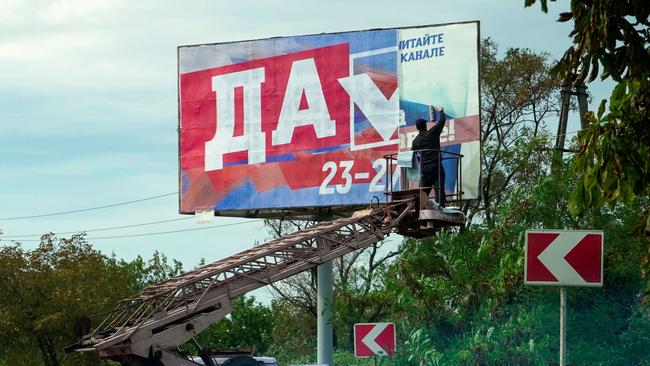 A man glues a referendum poster in Berdyansk.