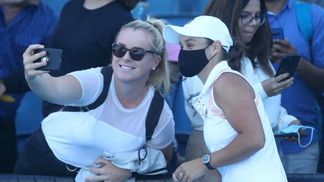 World No 1 Ash Barty poses for a photograph with a fan after her doubles win