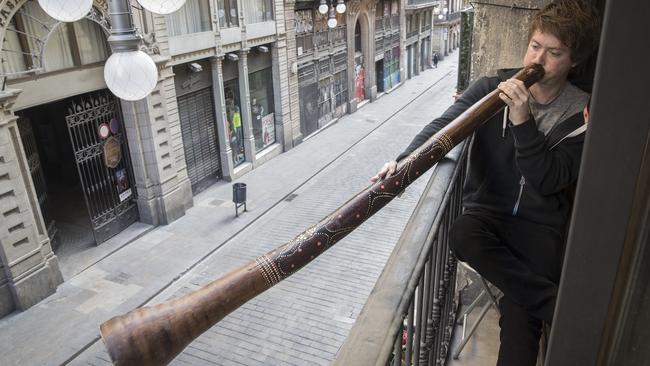 Australian Mark Carter playing his didgeridoo on his mother’s Barcelona balcony. Picture: Ella Pellegrini.