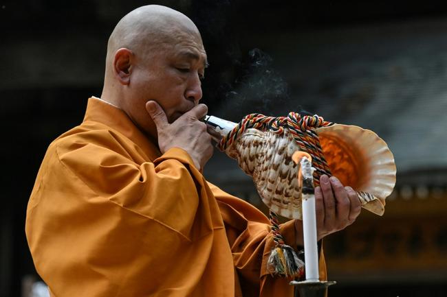 Japanese monk Yoyu Mimatsu blows into a conch at a ritual burning of thousands of paper cranes sent to his Buddhist temple near Hiroshima