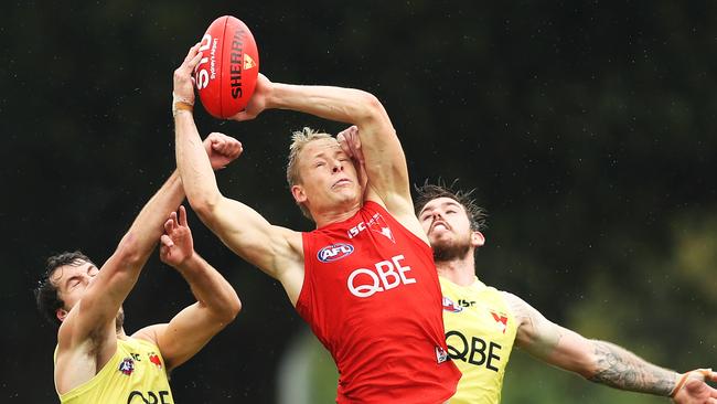 Isaac Heeney climbs above two teammates to mark at Sydney training.