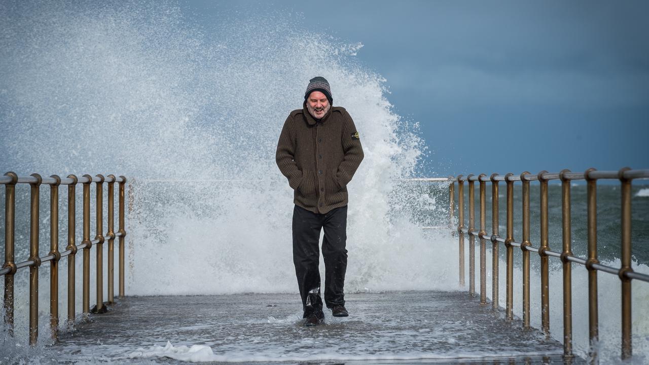 Clive Wansbrough strolls along the jetty at Middle Park as a bitter cold front and strong winds lash Victoria. Picture: Jake Nowakowski
