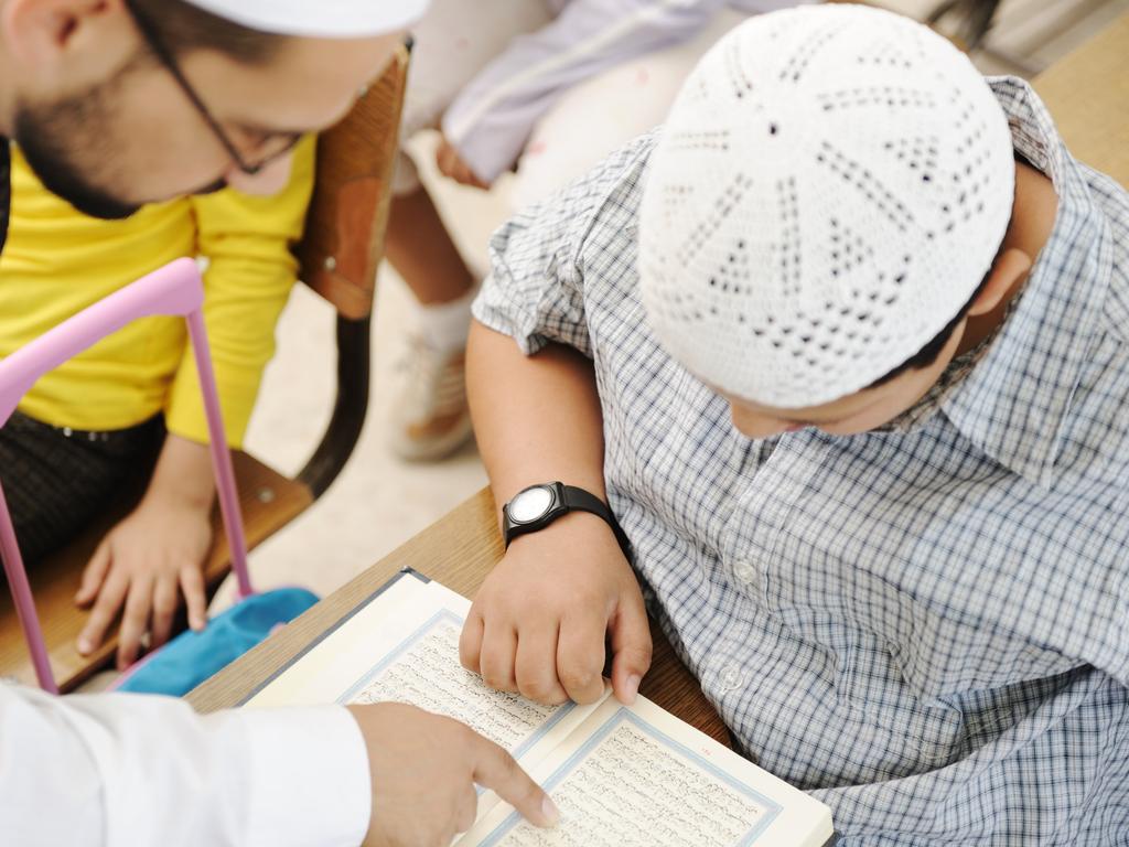 Education activities in classroom, Muslim teacher showing Koran to kid