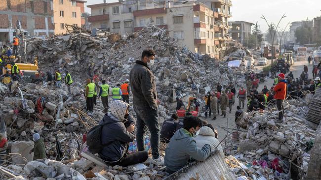 People stand the rubble of collapsed buildings during rescue operations in Hatay. Picture: AFP.