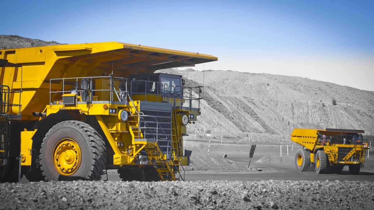 Two large yellow truck used in a modern coal mine in Queensland, Australia. Trucks transport coal from open cast mine. Fossil fuel industry, Environmental challenge. Climate Change. Logos removed.