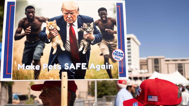 A man carries an AI-generated image of former US President and Republican presidential candidate Donald Trump carrying cats away from Haitian immigrants, a reference to falsehoods spread about Springfield, Ohio, during a campaign rally for Trump at the Tucson Music Hall in Tucson, Arizona, September 12, 2024. (Photo by Rebecca NOBLE / AFP)