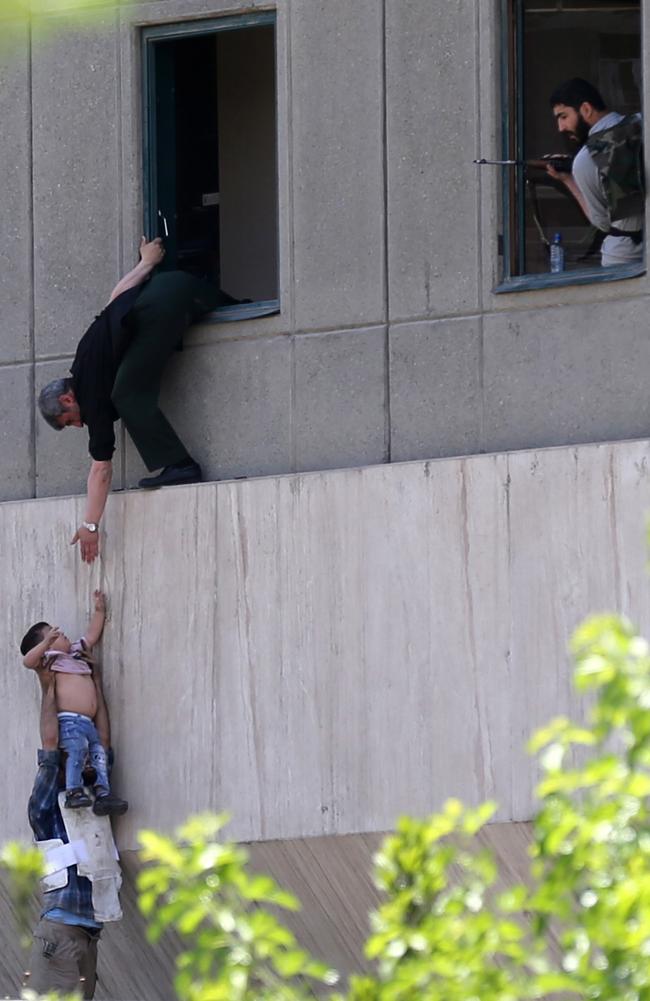 Iranian policemen evacuate a child from the parliament building in Tehran.  Picture:  AFP