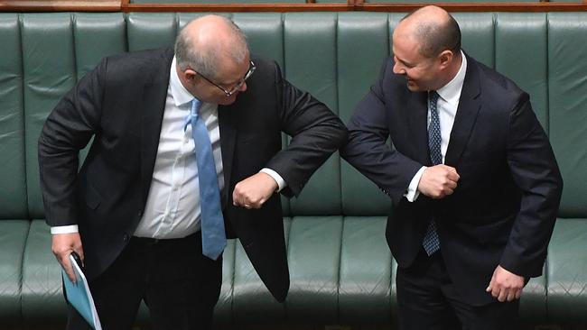 Prime Minister Scott Morrison bumps elbows with Treasurer Josh Frydenberg after the coronavirus Economic Response Bill was presented in the House of Representatives on April 8. Picture: Sam Mooy/Getty Images