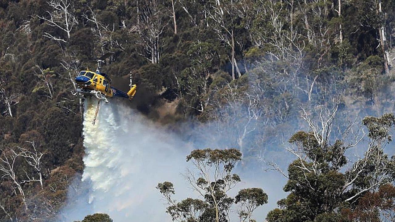 A McDermott Aviation Bell 214B water bomber drops 3000 litres of water near homes in Tasmania under threat from bushfire.