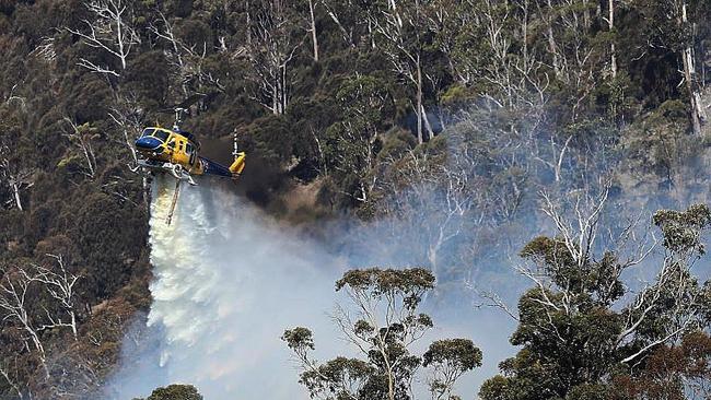 A McDermott Aviation Bell 214B water bomber drops 3000 litres of water near homes in Tasmania under threat from bushfire.