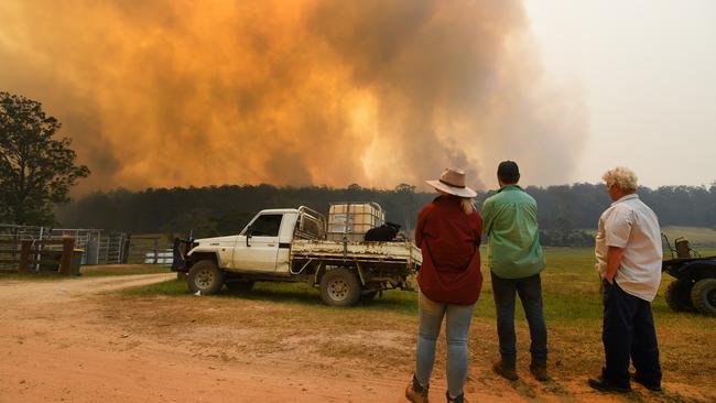 Locals watch smoke from a large bushfire outside Nana Glen, near Coffs Harbour, on Tuesday. About half the fires burning around the state are uncontained. Picture: AAP