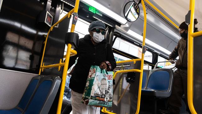 A woman wearing a protective mask gets on a city bus in New York. Picture: Getty Images