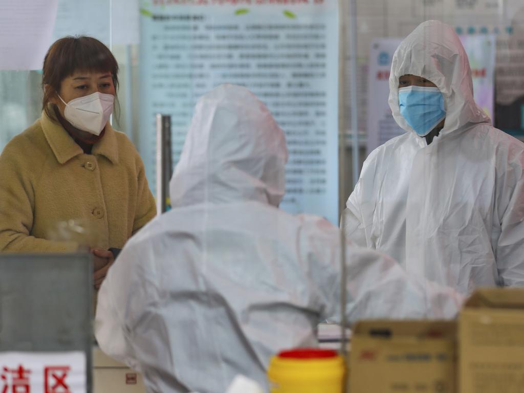 Medical workers in protective gear talk with a woman suspected of being ill with a coronavirus at a community health station in Wuhan. Picture: Chinatopix/AP