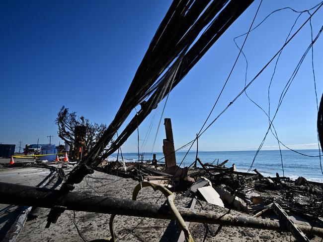 Downed power lines lie beside a fire-ravaged beachfront property along the Pacific Coast Highway in Malibu. Picture: AFP