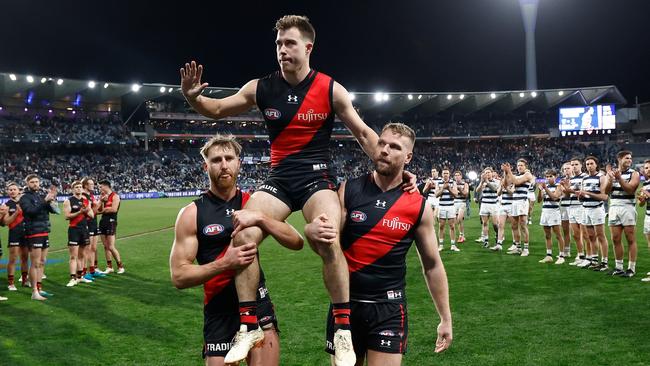 GEELONG, AUSTRALIA - JULY 15: Zach Merrett of the Bombers is chaired from the field after his 200th match by teammates Dyson Heppell (left) and Jake Stringer (right) during the 2023 AFL Round 18 match between the Geelong Cats and the Essendon Bombers at GMHBA Stadium on July 15, 2023 in Geelong, Australia. (Photo by Michael Willson/AFL Photos via Getty Images)