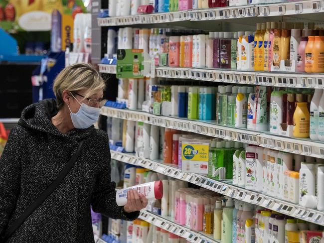 Shoppers wearing a face mask looks at hygiene products in a supermarket on March 16, 2020, in Pfastatt, eastern France, as people stock up on goods amid the outbreak of COVID-19, caused by the novel coronavirus. - The French president is due to address the nation on the evening of March 16, with many expecting him to unveil more strict home confinement rules in a bid to prevent the virus from spreading. France has closed down all schools, theatres, cinemas and a range of shops, with only those selling food and other essential items allowed to remain open. The balance sheet of the epidemic climbed to 127 dead and 5,423 confirmed cases in France. (Photo by SEBASTIEN BOZON / AFP)