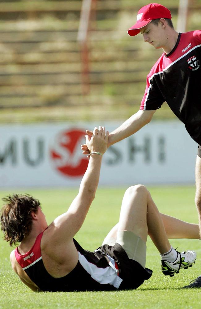 Andrew McQualter gives teammate Brendon Goddard a hand up at St Kilda training in 2005.