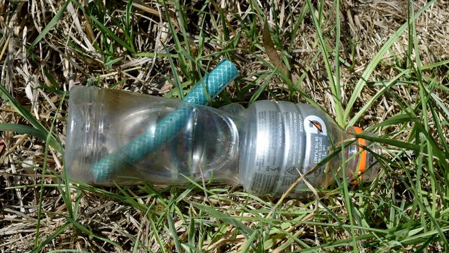 A makeshift bong lies discarded in the grass beside the lake.