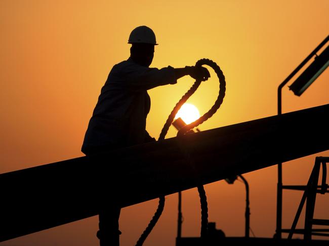 An unidentified oilfield worker ties pipes to be raised on an oil rig as the sun sets in the Persian Gulf desert oil field of Sakhir, Bahrain 07/07/2010.