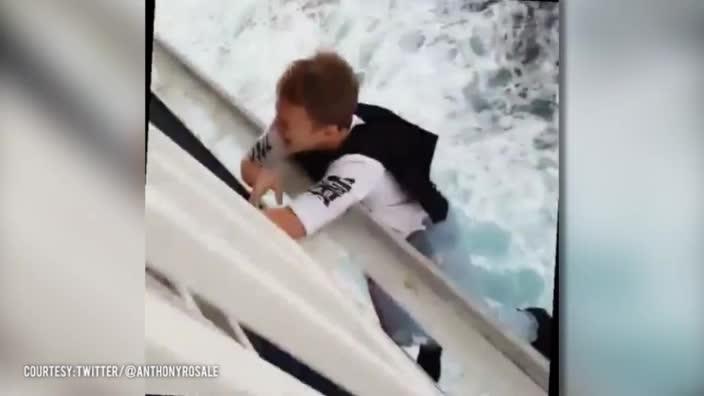 Idiot hangs off the side of a moving cruise ship