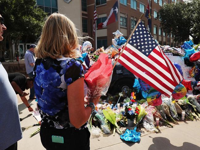 People visit a growing memorial at the Dallas police department's headquarters following the deaths of five police officers on July 10, 2016 in Dallas, Texas.