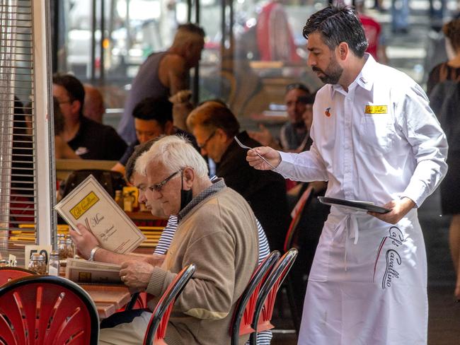 MELBOURNE, AUSTRALIA - NewsWire Photos December 13 2020: Waiters working  on a busy Lygon St Carlton on Sunday afternoon. Hospitality staff could be paid as much as $1000 in sign-on bonuses as Melbourne venues work desperately to find enough staff to meet demand from fresh out of lockdown residents.Picture: NCA NewsWire / David Geraghty