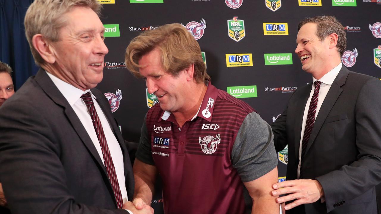 Des Hasler shakes hands with Manly CEO Lyall Gorman as Chairman Scott Penn looks on.