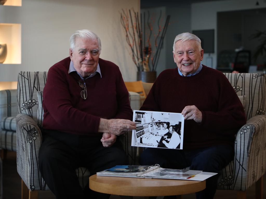 Mike Dinn and John Saxon holding a photo of them in the operations room at Honeysuckle Creek tracking station.