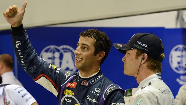 Red Bull Racing driver Daniel Ricciardo of Australia, left, waves to the crowd while Mercedes driver Nico Rosberg of Germany looks on after the qualifying session of the Formula One Singapore Grand Prix.