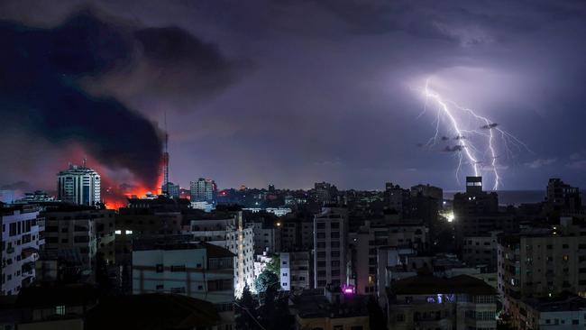 Lightning strikes as smoke billows following Israeli bombardment of Gaza City on October 9, 2023. Israel imposed a total siege on the Gaza Strip on October 9 and cut off the water supply as it kept bombing targets in the crowded Palestinian enclave in response to the Hamas surprise assault it has likened to the 9/11 attacks. (Photo by MOHAMMED ABED / AFP)