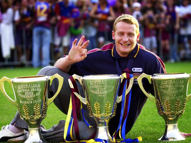 SEPTEMBER 28, 2003: Captain Michael Voss counts out three trophies for three consectutive title wins, 2001 (R), 2002 and 2003 (C), as the victorious Brisbane Lions AFL team returns to the Gabba in Brisbane 28/09/03, the day after their grand final victory. Pic Patrick Hamilton.Australian Rules / Trophy