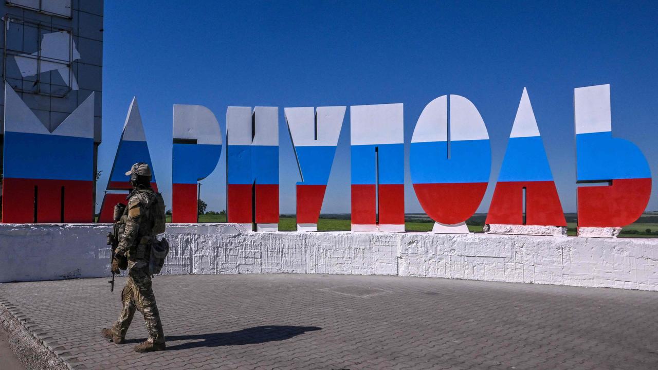 A Russian serviceman walks near a welcome sign reading "Mariupol", which has been painted in Russian flag colours, at the entrance of occupied Mariupol on June 12, 2022, amid the ongoing Russian military action in Ukraine. (Photo by Yuri KADOBNOV / AFP)