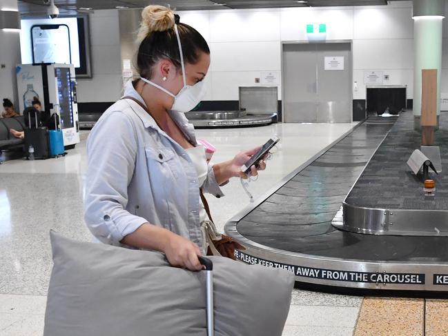 A women is seen walking past an empty baggage carousel at the Brisbane domestic airport terminal in Brisbane, Monday, March 23, 2020. The Queensland Government has announced that they will close the state's borders to stop the spread of the Coronavirus (COVID-19) outbreak, beginning at midnight on Wednesday and they will force anyone entering Queensland to quarantine themselves for 14 days after their arrival. (AAP Image/Darren England) NO ARCHIVING