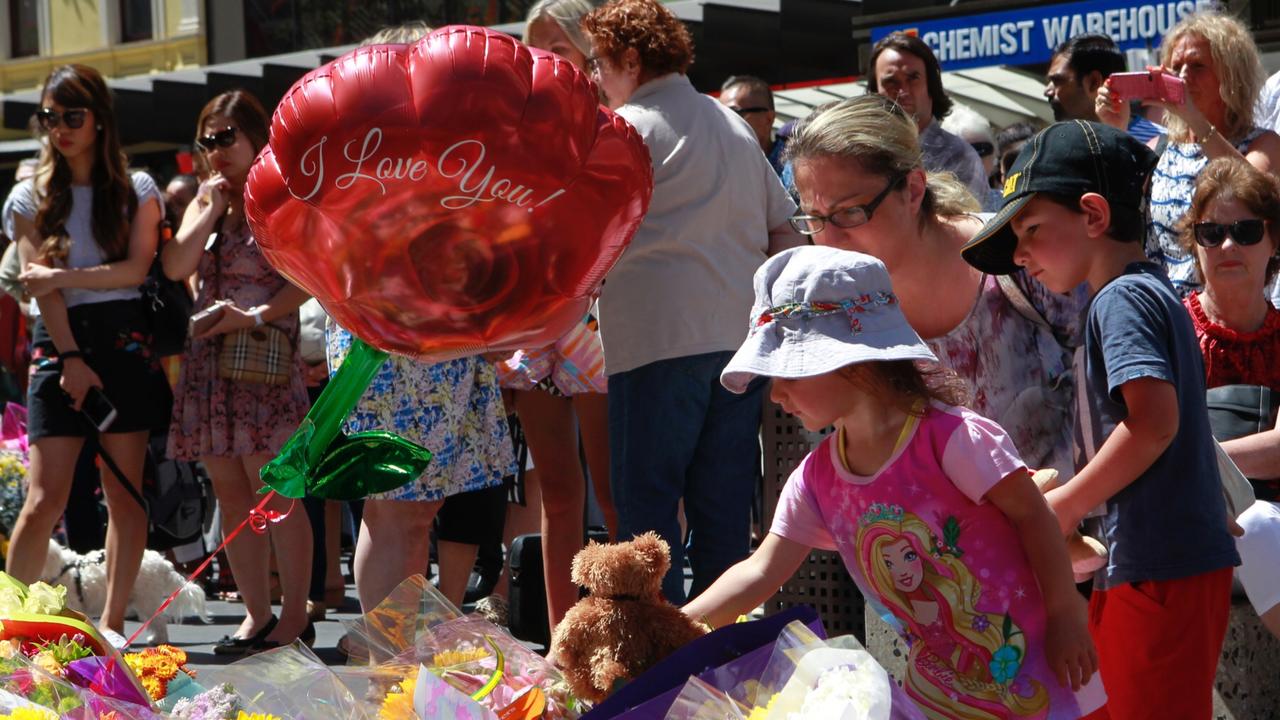 Members of the public laying flowers and touching tributes at a public memorial site for the Bourke St tragedy last year. Picture: David Crosling