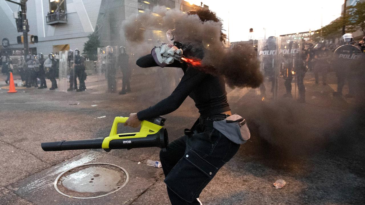 A protester throws a smoke device at police during a protest in Atlanta. Picture: AP/John Bazemore