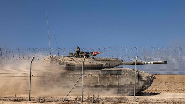 An Israeli Merkava tank drives past a fence near Kibbutz Beeri, close to the border with Gaza. Picture: AFP