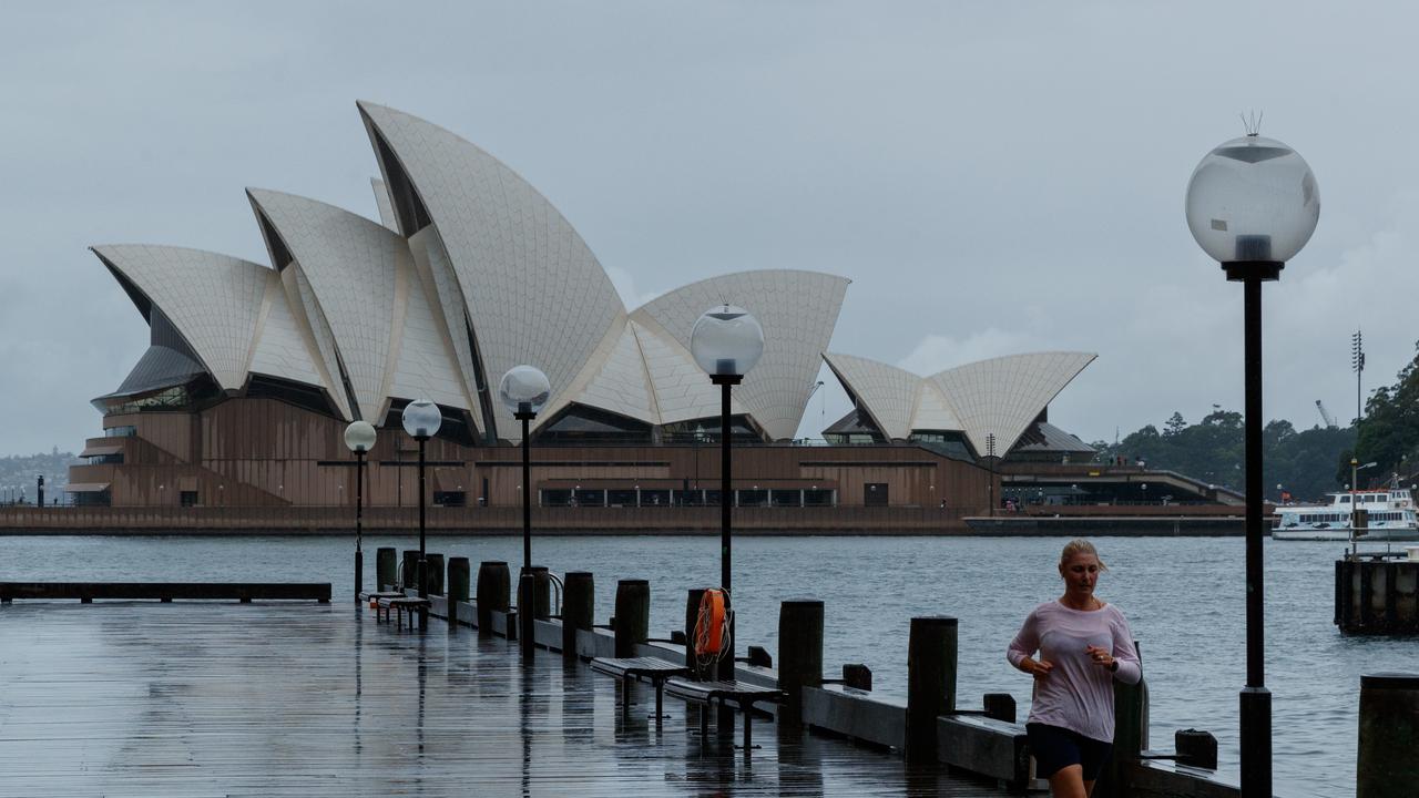 A lone jogger pushes past the weather for a run past the Opera House. The rain is expected to cease on Monday. Picture: NCA NewsWire / Max Mason-Hubers