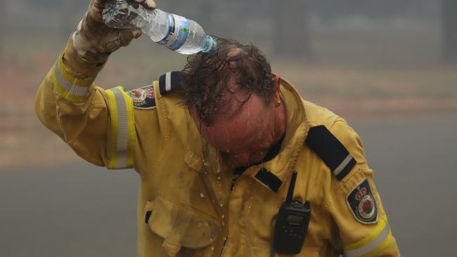 RFS firefighter Brendon Ede cools himself down with a bottle of water. Picture: Rohan Kelly