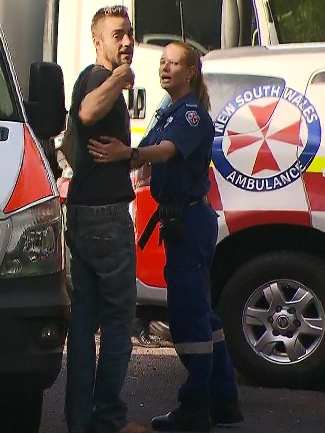 A man believed to be a family member speaks to a paramedic at the Robertson Lookout carpark on Tuesday. Picture: TNV