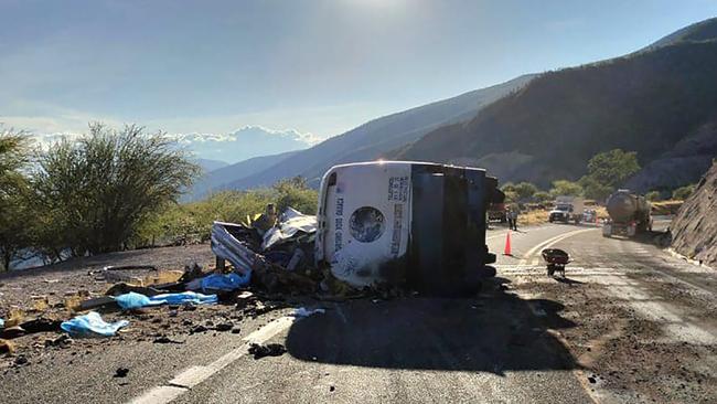 The wreckage of the bus lying on its side on a highway winding through hills. Picture: AFP/ Mexico’s Civil Protection