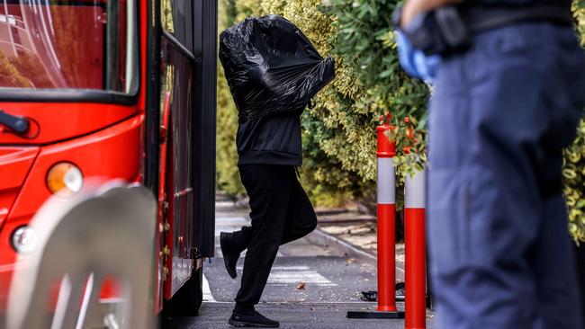 A traveller wearing a bag over their head arrives at a hotel in Albert Park, Melbourne, after being evacuated from the Holiday Inn in the CBD. Picture Ian Currie