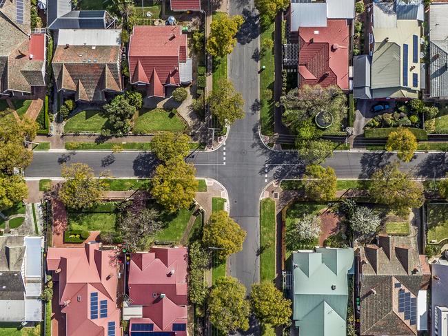 Aerial view of leafy eastern suburban houses on 4-way cross road intersection in Adelaide, South Australia: directly above, rooftop solar, trees. Housing property generic