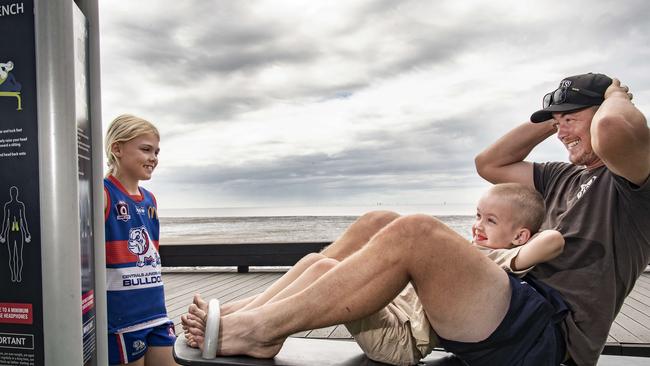 Dad Jason Campbell and his son William (6) do sit-ups on the Esplanade gym equipment watched by daughter Ella (9). Picture: Brian Cassey