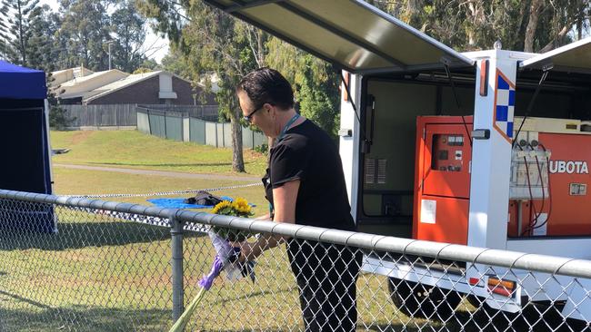 A woman lays flowers at the scene in Frascott Park, Varsity Lakes, where Harrison Geppert died. Picture: Annie Perets.