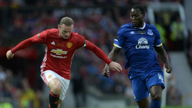 Manchester United's English striker Wayne Rooney (L) runs with the ball challenged by Everton's Belgian striker Romelu Lukaku (R).