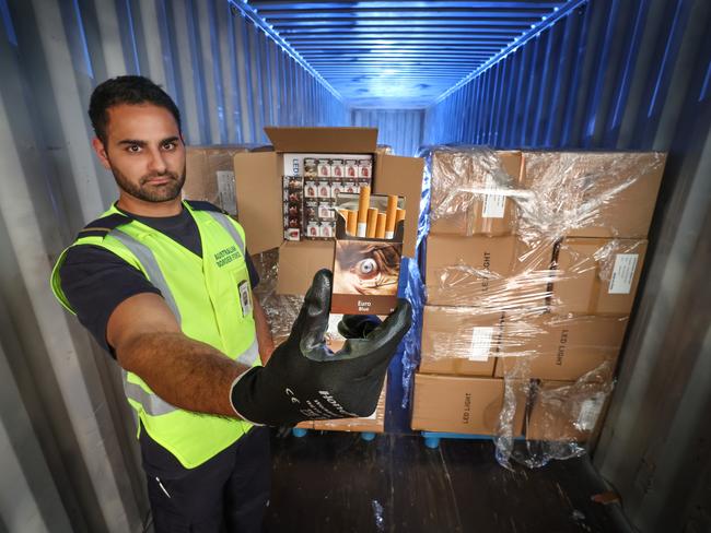 An Australian Border Force Customs officer with a concealed shipment of cigarettes boxed as LED lights from China found in a container. Picture: David Caird