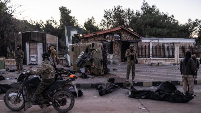 Members of the Syrian armed opposition forces stand around bodies of dead members of the Syrian regime who were killed as opposition fighters seize control of most parts of Aleppo. Picture: Reuters